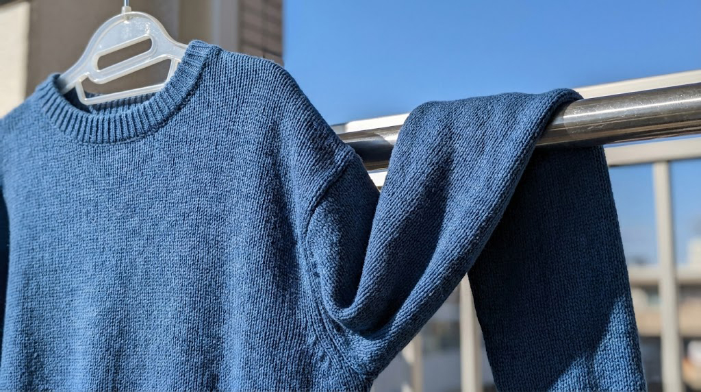 ニットの袖を物干し竿にかけて肩への負担を減らす袖通し干しの実例