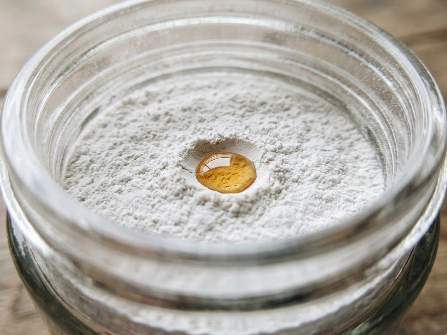 ガラス瓶の白い粉末にドテラの精油を1滴垂らしたクローズアップ写真