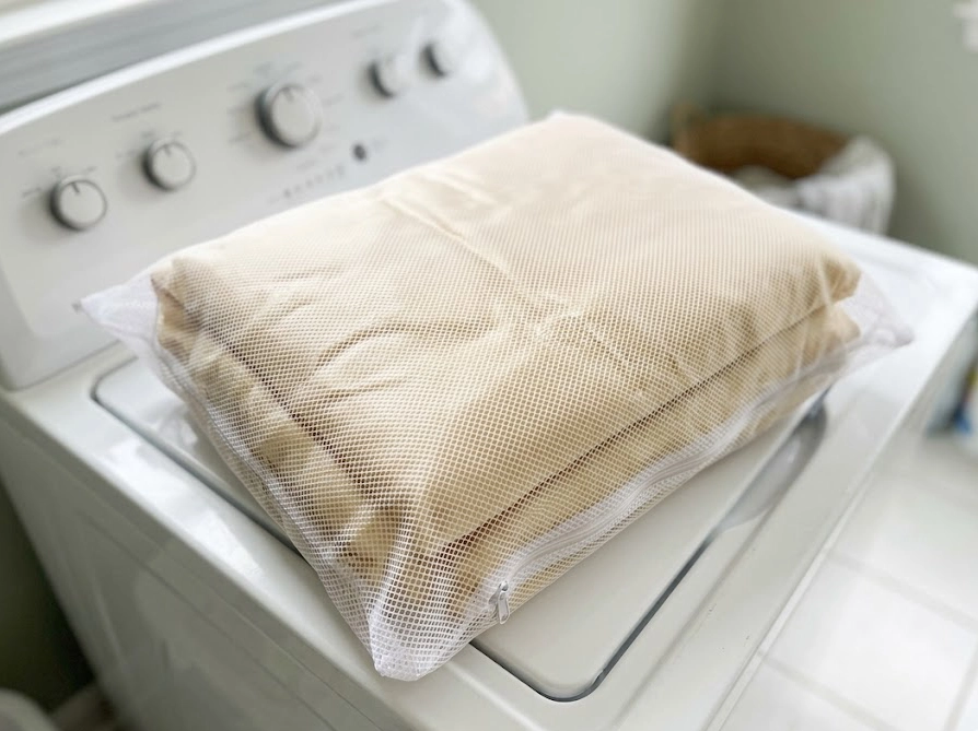 大判の洗濯ネットにきれいに畳んで入れたシルク毛布を洗濯機の上に置いた様子