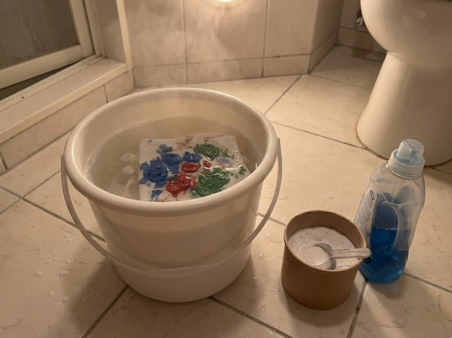 バケツのぬるま湯に布をつけおき洗いしている様子の写真