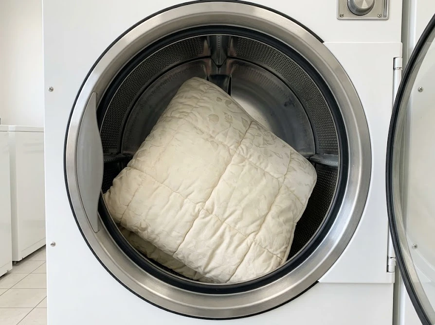正方形のこたつ布団が十分な余裕を持って中型の洗濯乾燥機に収まっている様子