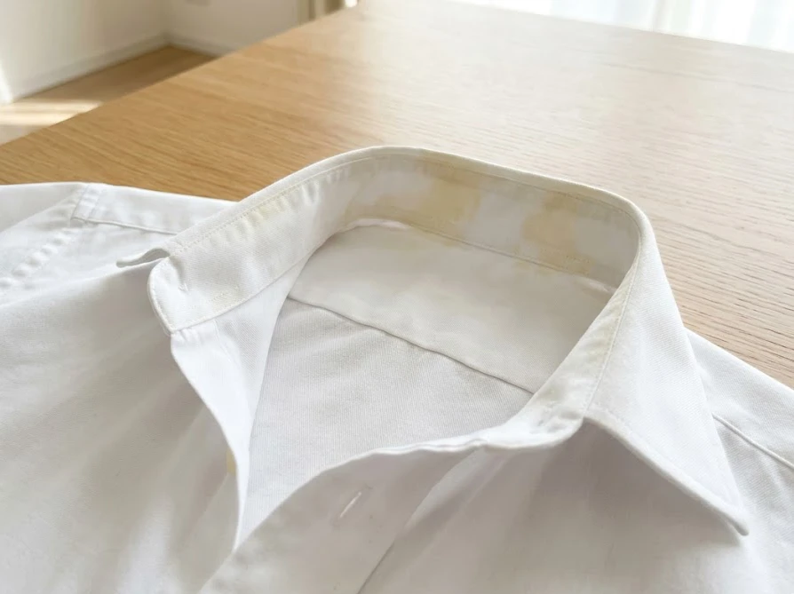 日光の当たる場所で、襟元の黄色い皮脂汚れが目立つ白いワイシャツ