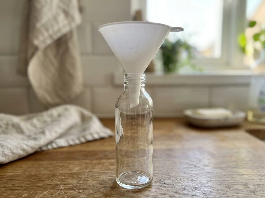 底をしっかり支えながら、詰め替えパックから透明ボトルへ洗剤を注ぐ様子