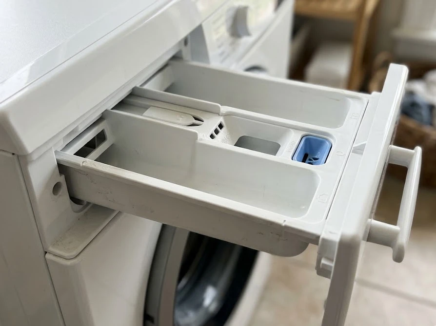 詰め替えを入れすぎないように引き出された、清潔な洗濯機の洗剤投入口