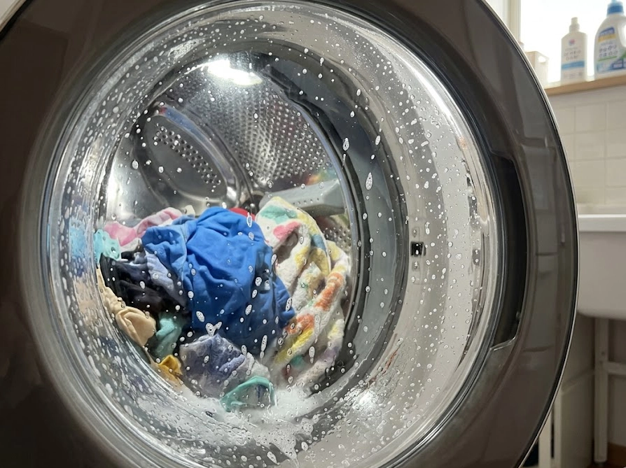 洗濯機の中で泡立ちながら洗われる衣類。季節に合わせた投入量調整の様子