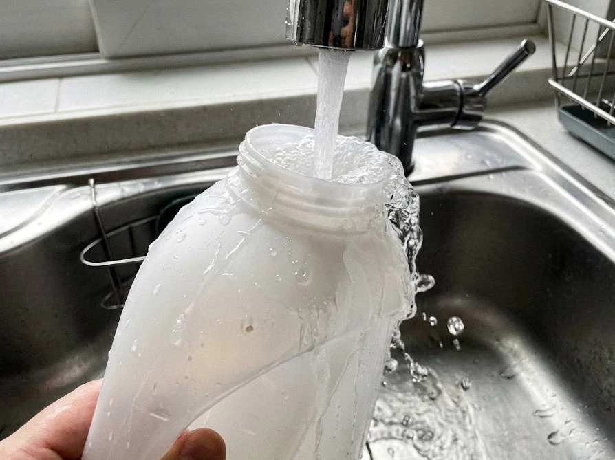 洗面所で自動投入タンクを水洗いする様子。定期的なお手入れとメンテナンス