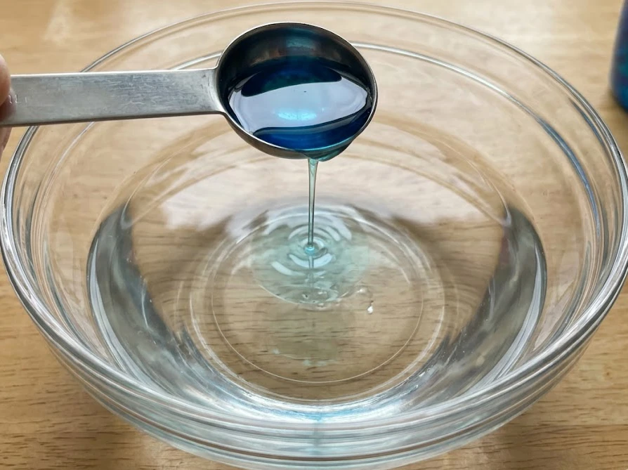 固まらない原因を防ぐため、アリエールをスプーンで少しずつボウルに加えている様子