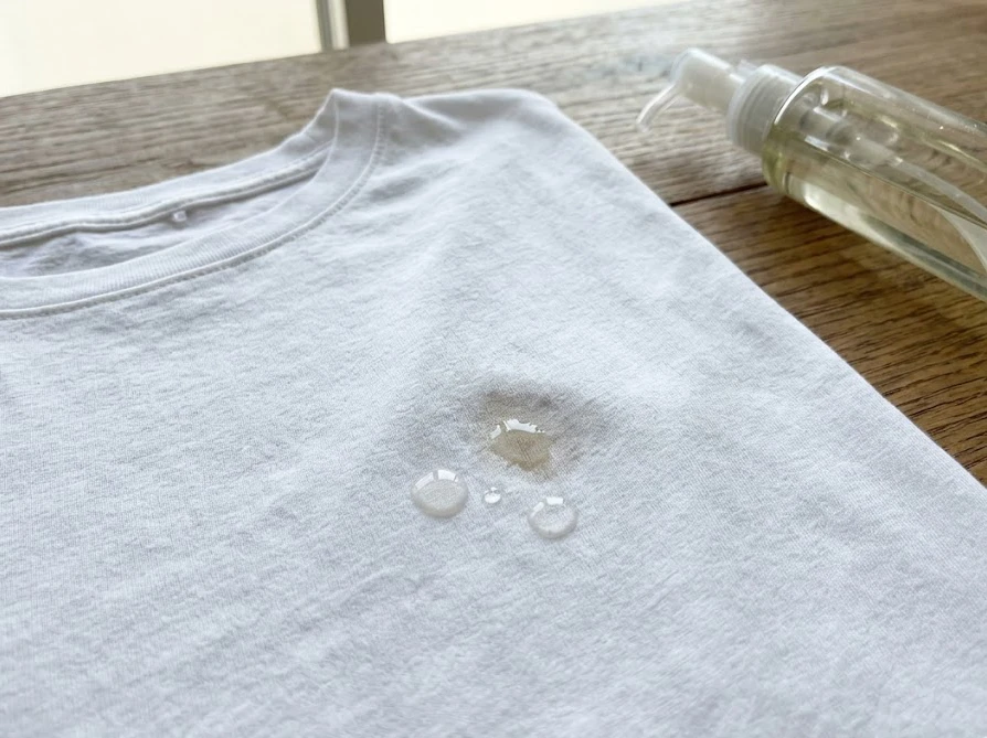 乾燥してしまったTシャツの油染みにクレンジングオイルを垂らして対処する様子